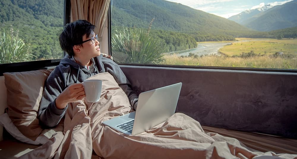 Man working from his camper van with a mountain view.