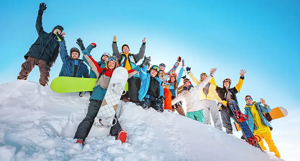 Large group of snowboarders on top of a snowy slope