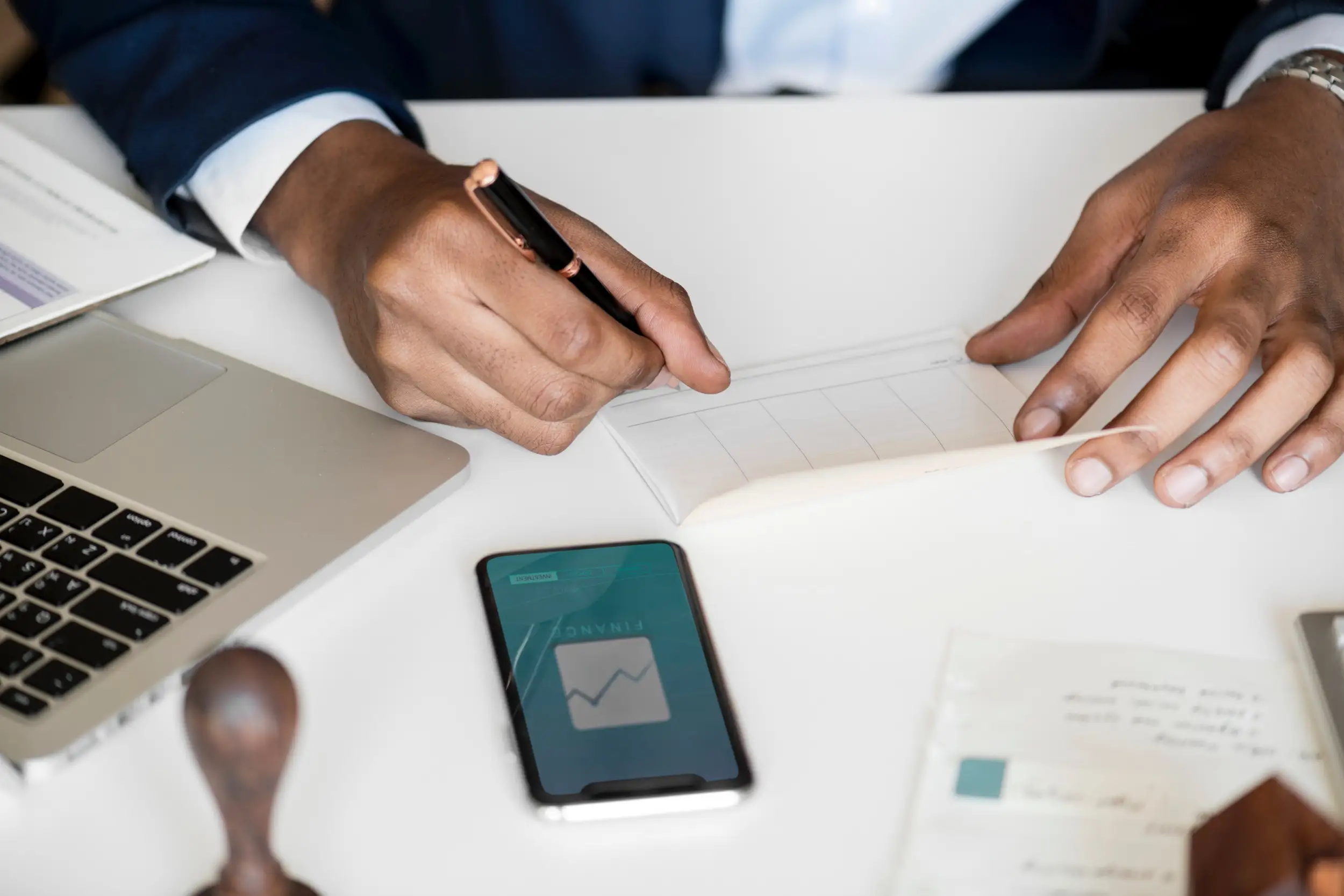 Man in suit signs paperwork at a desk