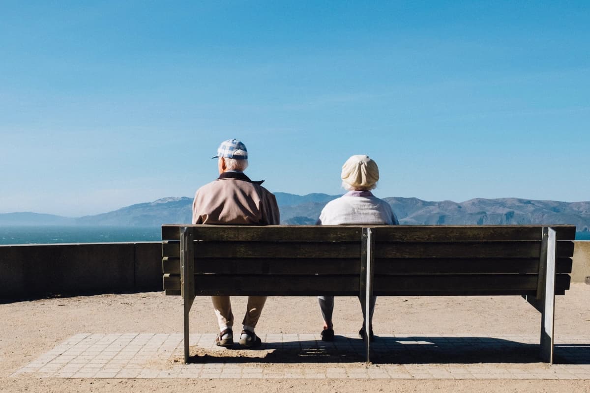 Older couple sits together on a park bench