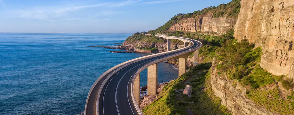 Coastal road winds between ocean and cliffside