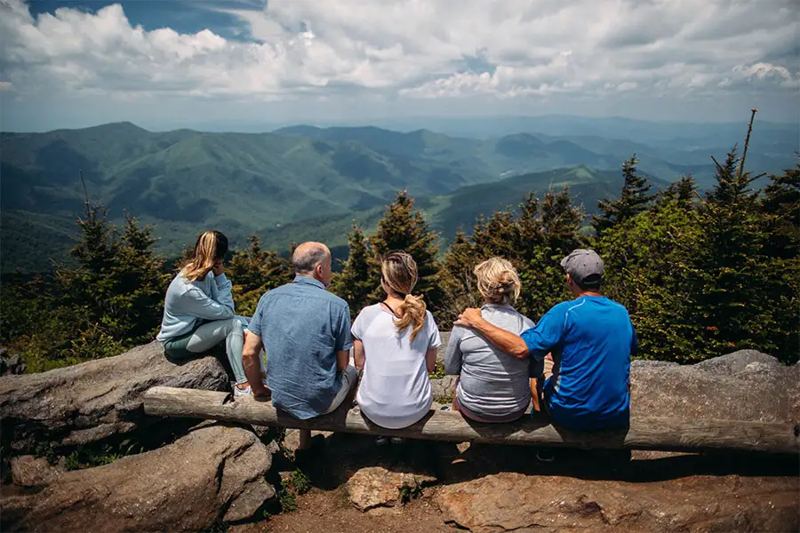 Family of 5 sit on a log during hike in the mountains