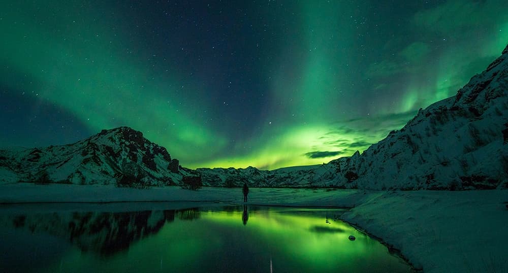 Green Northern Lights in the snowy mountains